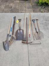 Group of assorted yard tools, rakes, shovels, post hole digger
